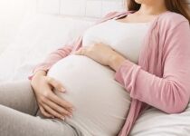 Pregnancy and rest. Young millennial pregnant woman lying in bed, panorama with free space