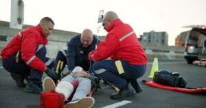 Emergency medical technicians (EMTs) attending to an injured person on the road. The image highlights concerns about potential EMT negligence in providing timely and adequate medical care.