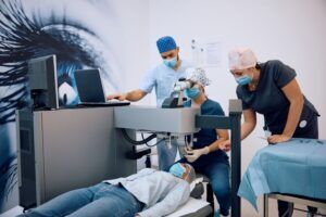 team of medical professionals performing eye surgery in a modern operating room. A patient lies on the table while a surgeon operates a laser machine, assisted by two staff members. Another specialist monitors a computer screen. The setting emphasizes the importance of precision in ophthalmic procedures and the potential risks of malpractice in eye surgery.