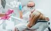 dentist and dental hygienist looking over patient in chair with dental tools