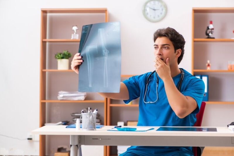 Un médico examinando una radiografía con una expresión sorprendida, representando las causas comunes de los errores de diagnóstico.