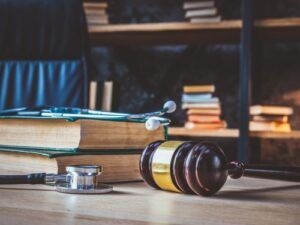 A wooden gavel, medical books, and a stethoscope on a lawyer's desk, symbolizing the legal complexities of medical malpractice vs. medical negligence cases. Understanding the difference is crucial when pursuing justice for medical errors.